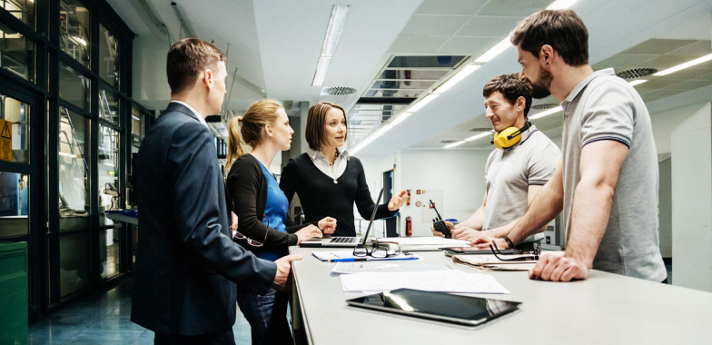 Workgroup standing round a table listening to a manager