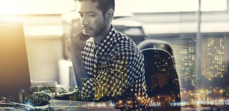 Man sitting in office in front of his computer thinking