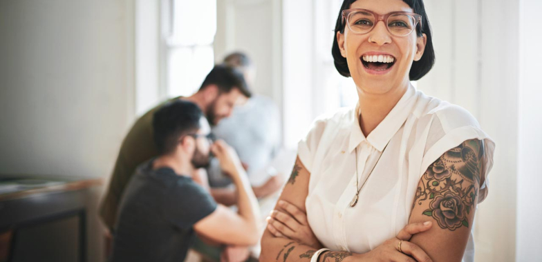 Woman smiling at camera with work colleagues in background working