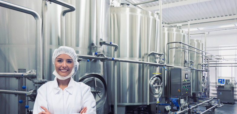 Female worker in full PPE in front of large vats
