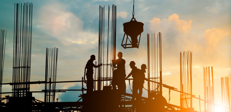 Construction workers on site at sunset