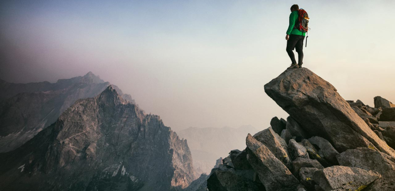Man standing on a rocky outcrop high in the mountains 