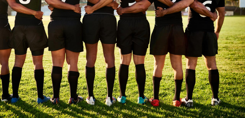 Rugby players in a line with arms round each other facing away from camera