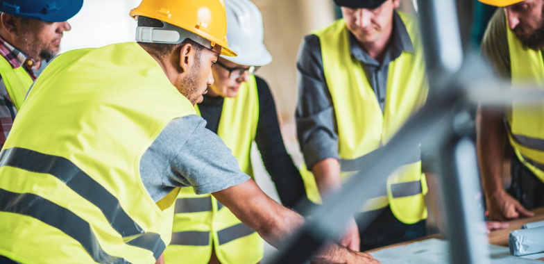 Building site workers around table looking at plans