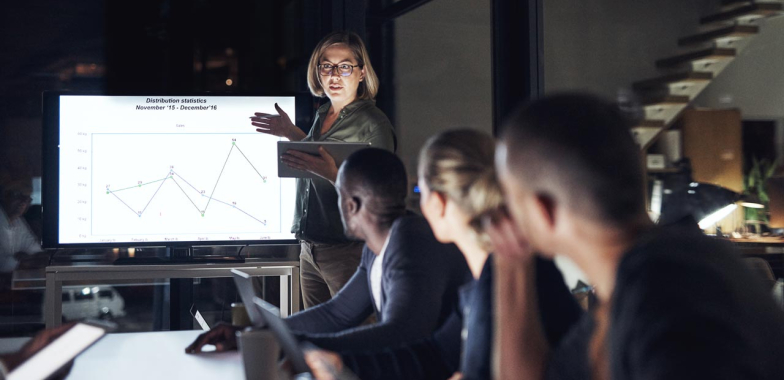 Female leader talking to her team round a table with a whiteboard