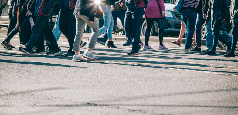 People from the waist down walking across a road crossing