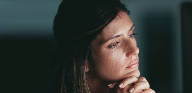 Close up of woman, chin on her hands looking thoughtfully to the right