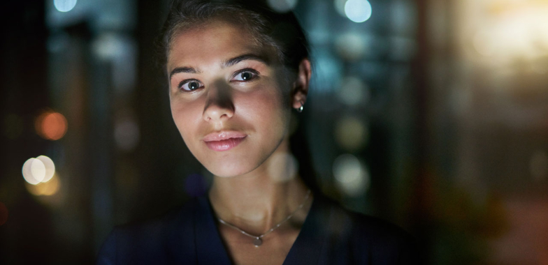 Woman with dark background looking at camera, head and shoulders