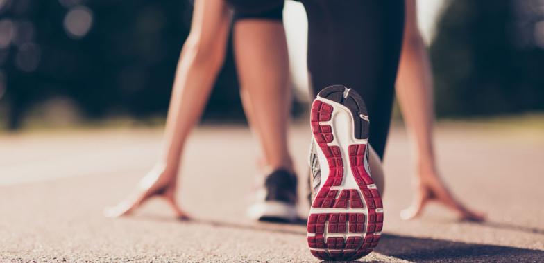 Female sprinter crouching bat starting blocks from behind