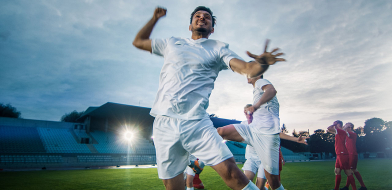 Soccer players walking on a pitch with one punching the air in celebration