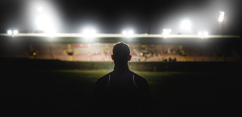 Outline of a rugby player in a stadium under lights