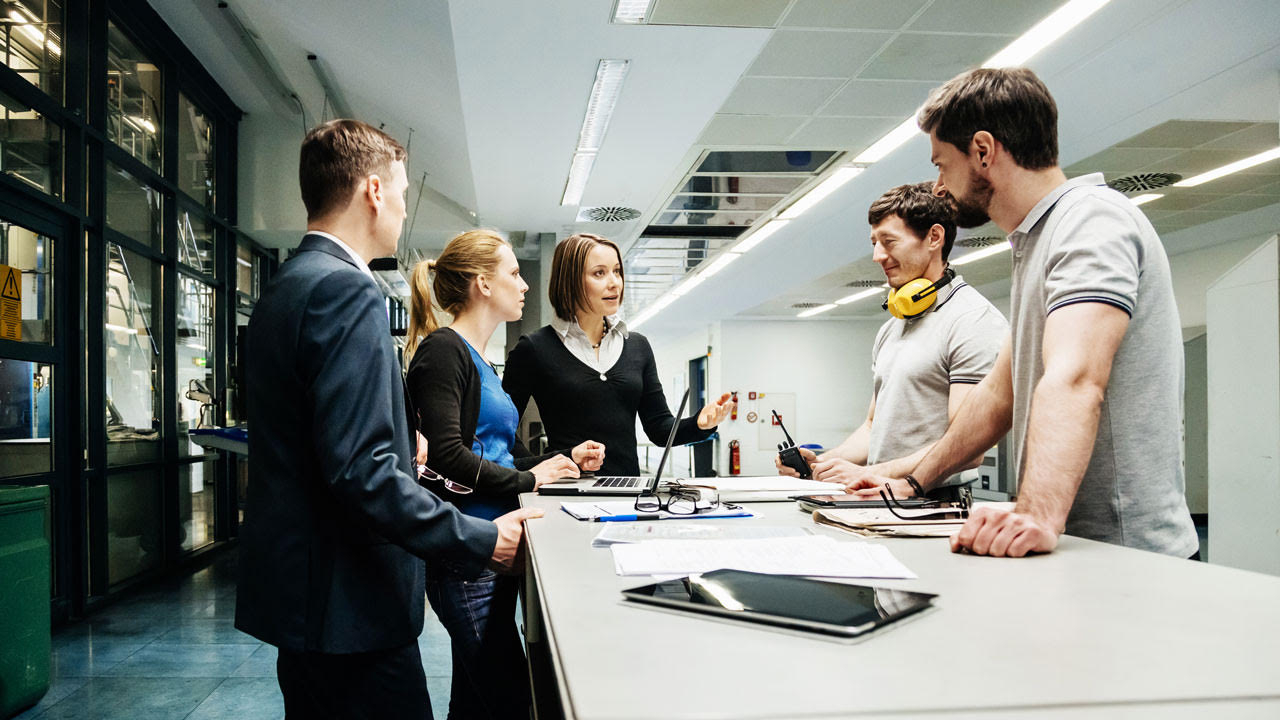 Workgroup standing round a table listening to a manager