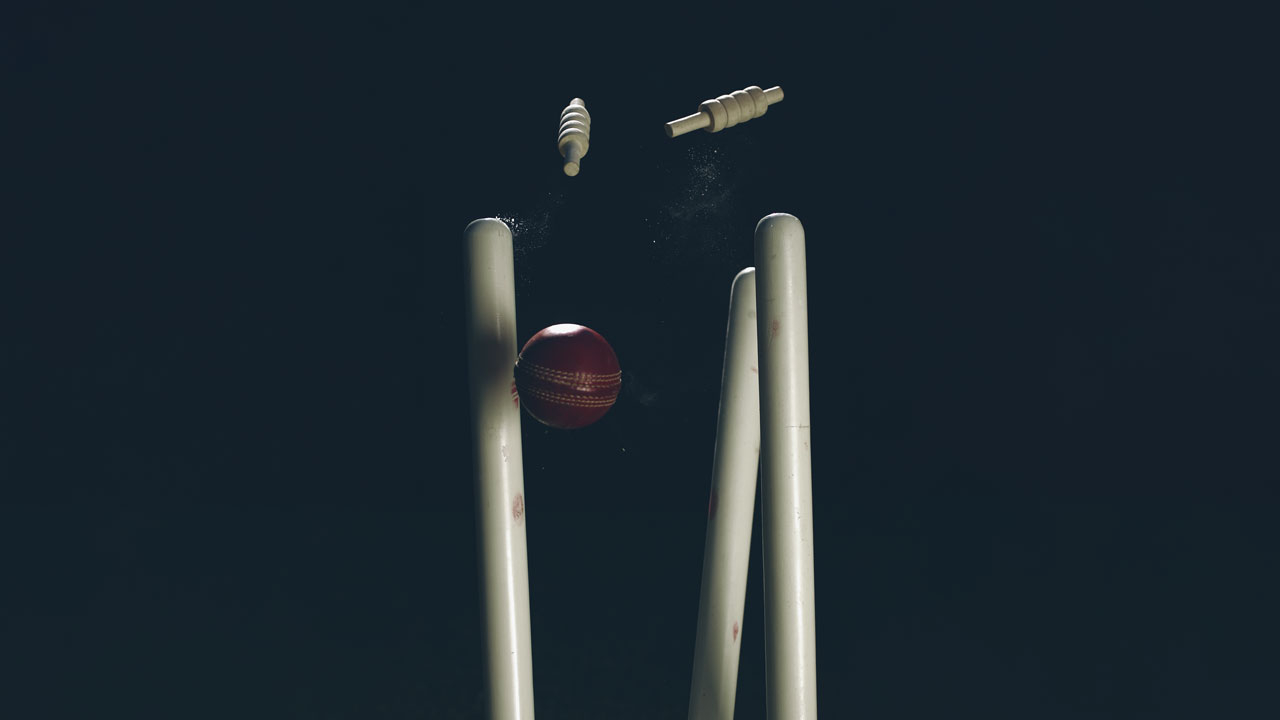 Cricket stumps being knocked over by a cricket ball